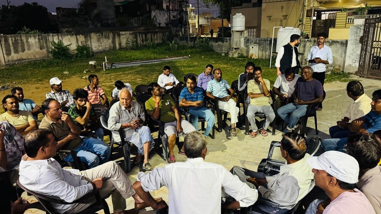 खुली जनसभा में प्लास्टिक कुर्सियों पर बैठे नगरवासी